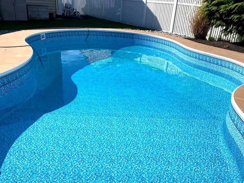 Une grande piscine bleue avec une clôture blanche en arrière-plan.