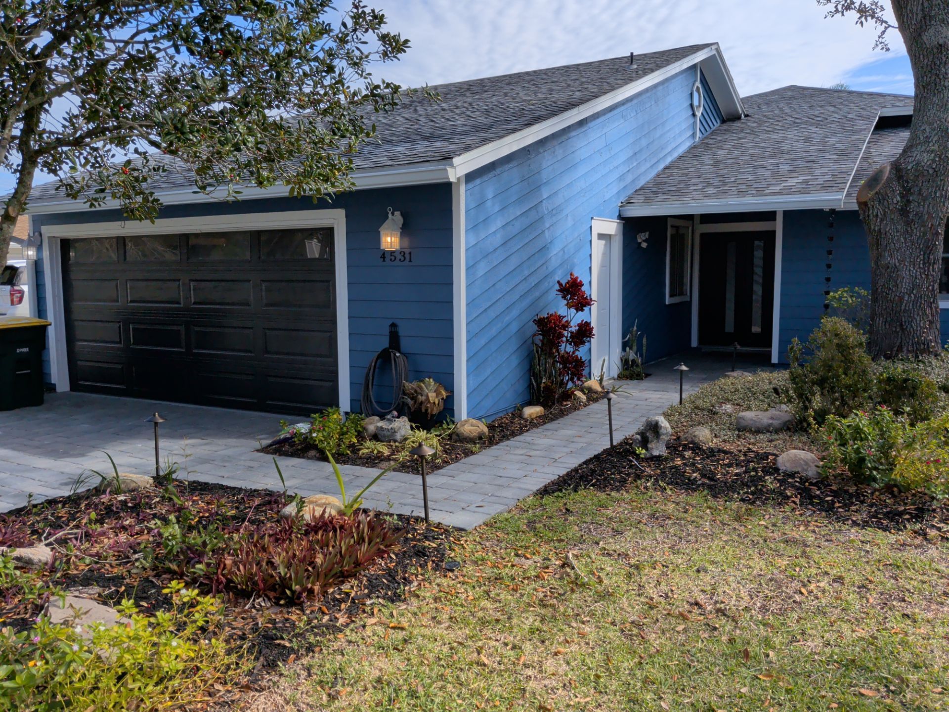 Blue suburban house with a two-car garage, front walkway, and landscaped yard