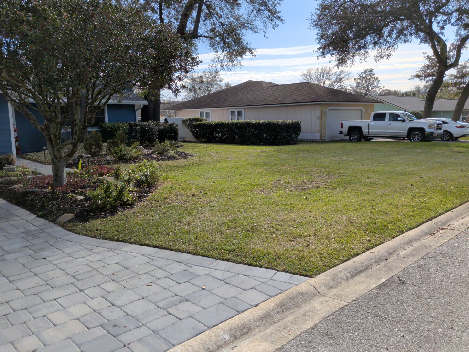 Suburban house with a front lawn, driveway, parked white truck, and landscaped flower bed
