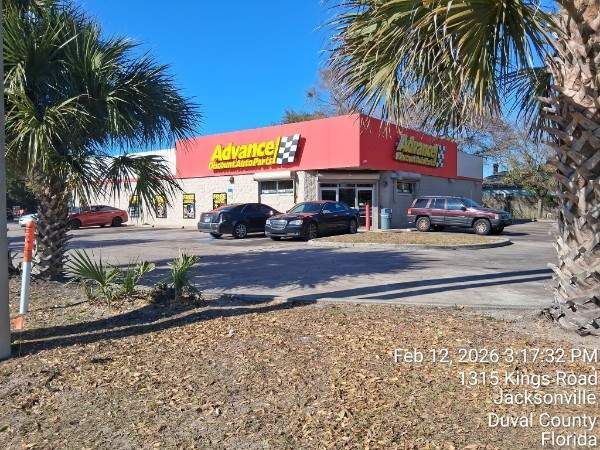Discount store with red roof and yellow sign, cars parked outside on a sunny day.