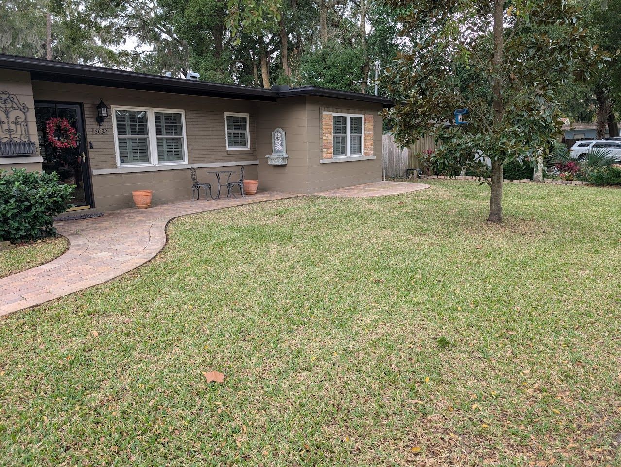 Tan house with a green lawn and a stone walkway. A tree is in the yard.