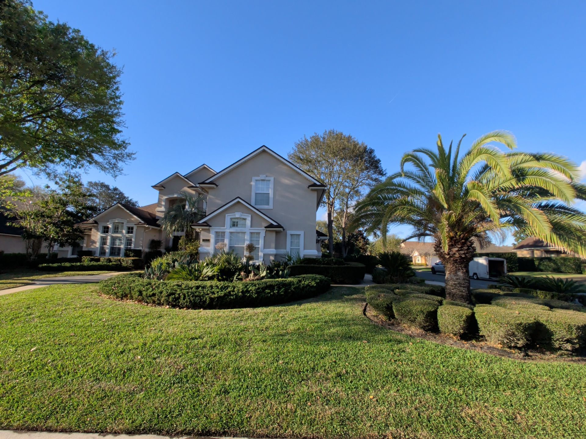 Suburban house with a manicured lawn and palm tree under a clear blue sky