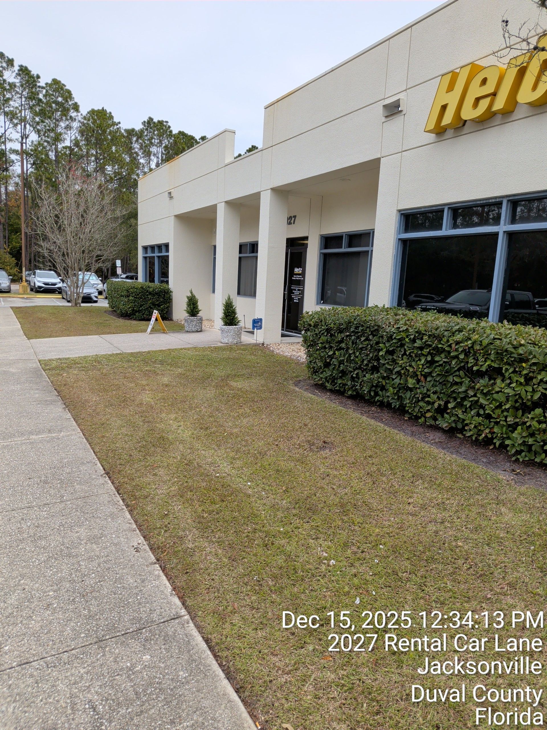 Heritage Bank storefront with white columns, dark windows, hedges, and a sidewalk in front