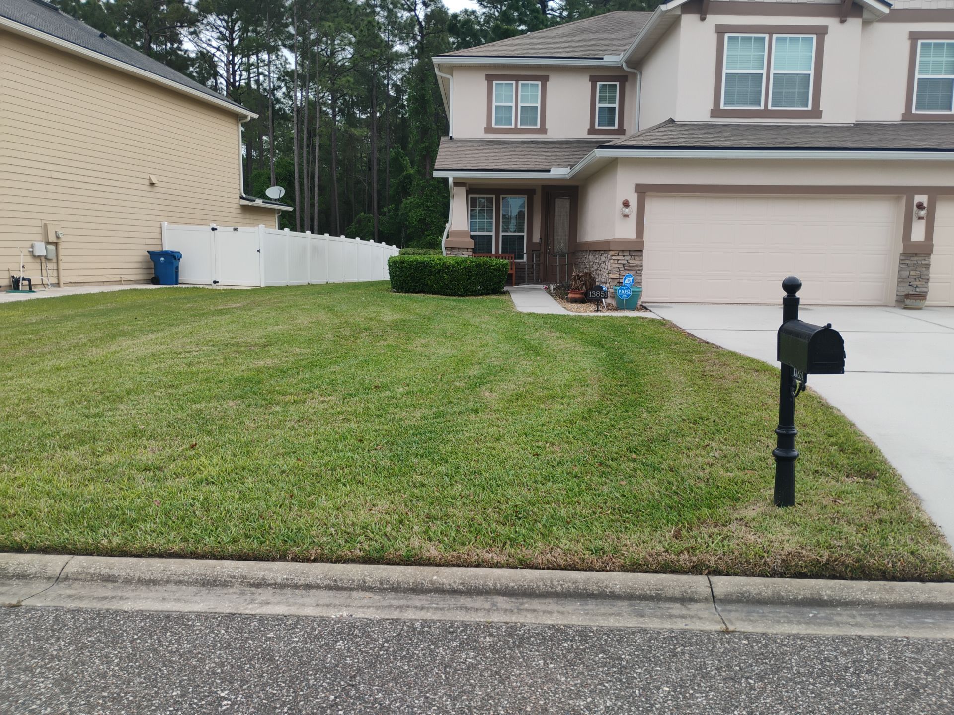 Suburban house with two-car garage, front lawn, and black mailbox by the curb.