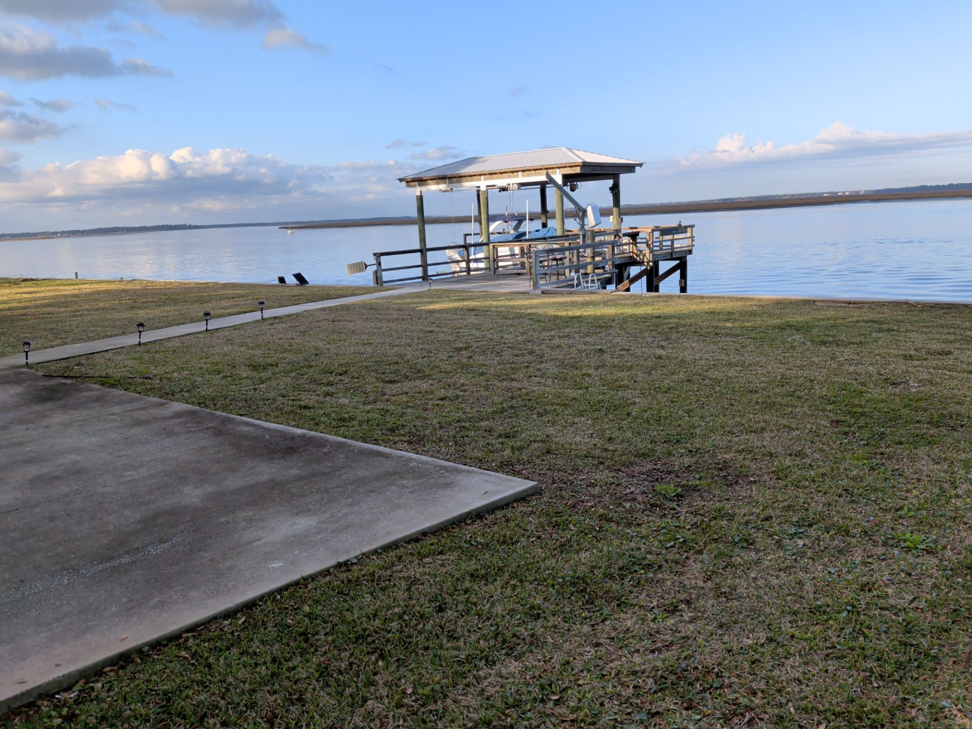Concrete ramp leading to a lakeside dock with a covered platform and calm water at sunset