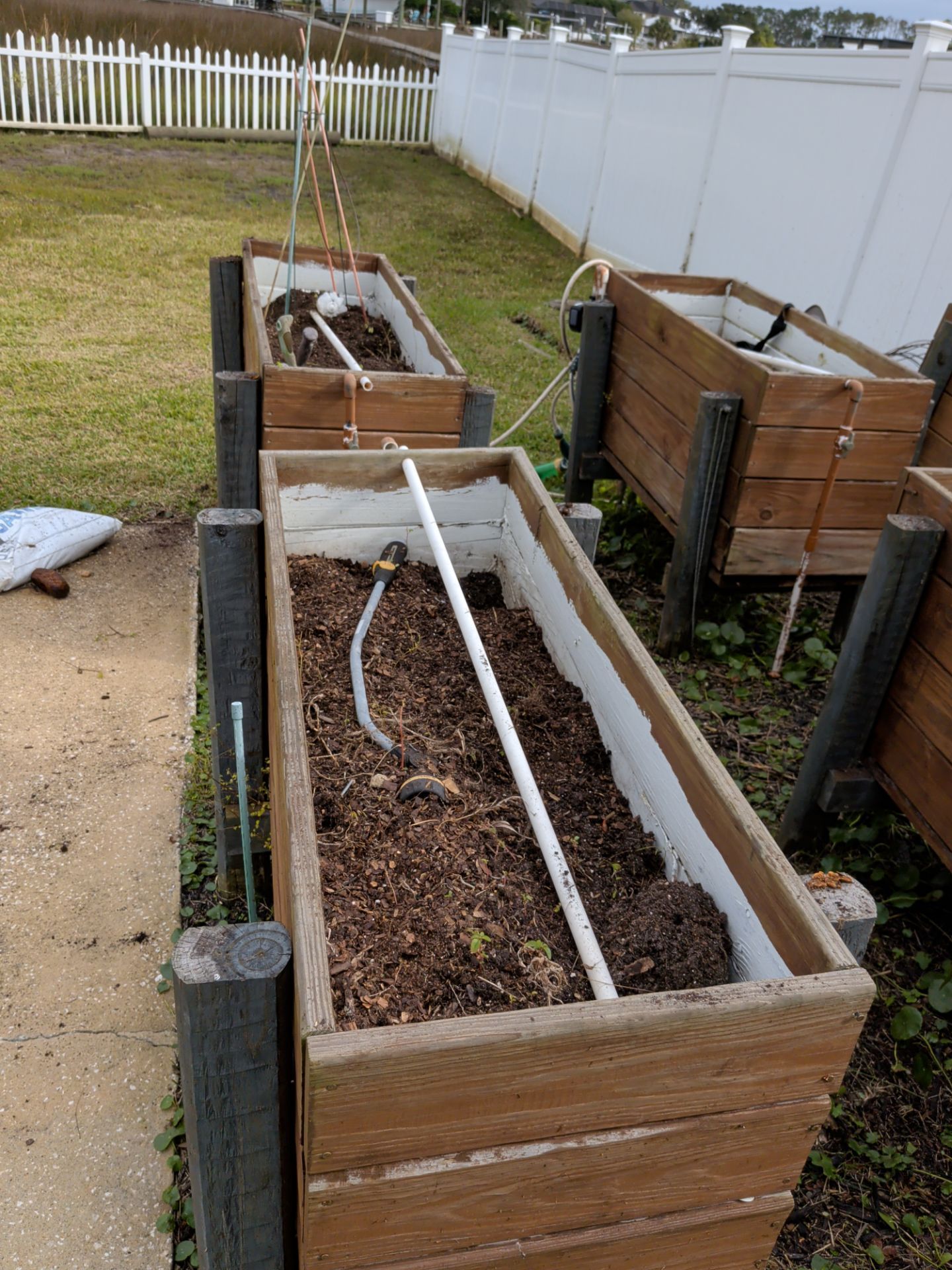 Raised garden beds with mulch and white hoses in a backyard yard