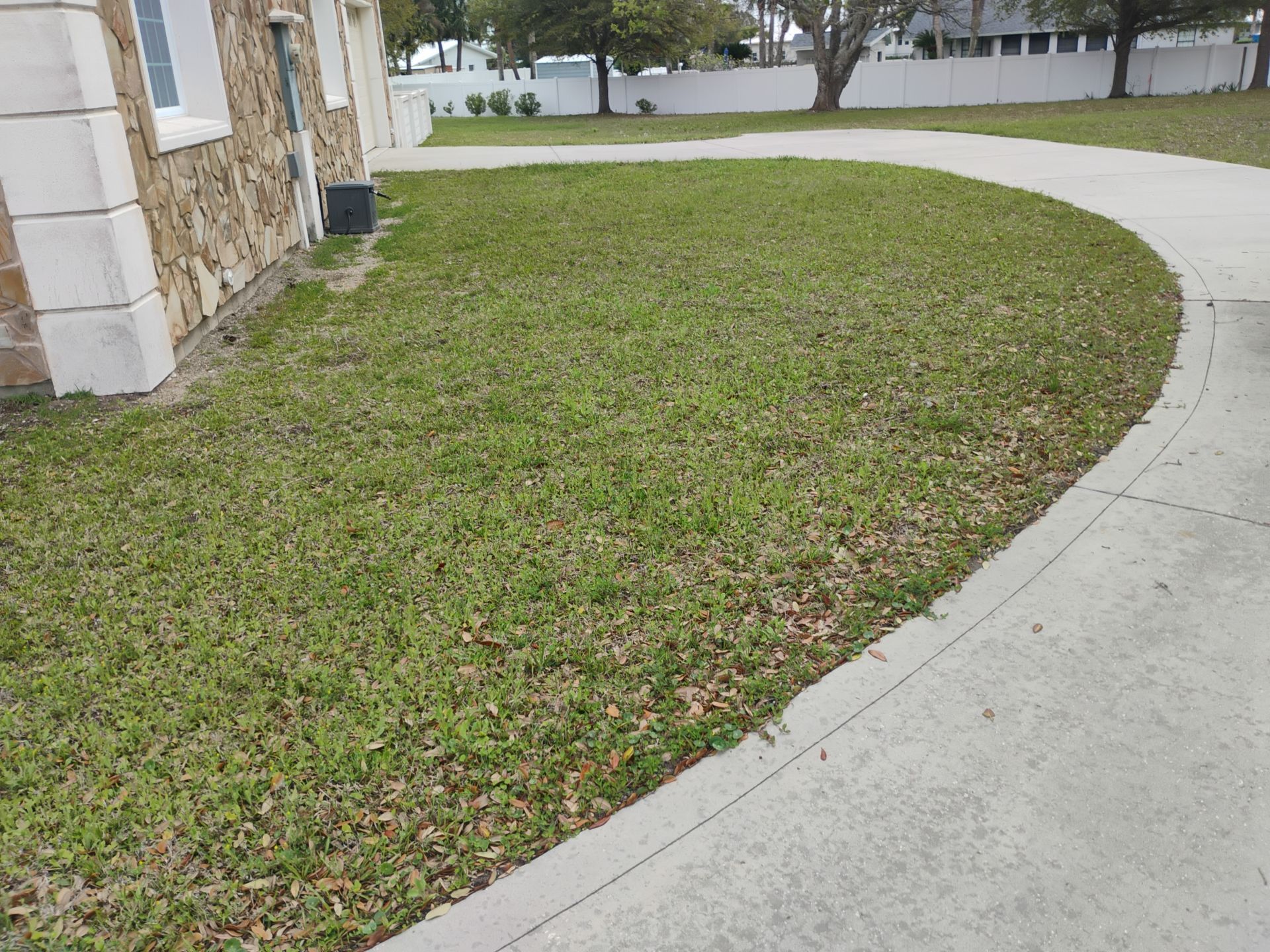 Curved sidewalk beside a stone building and a grassy lawn in a residential area