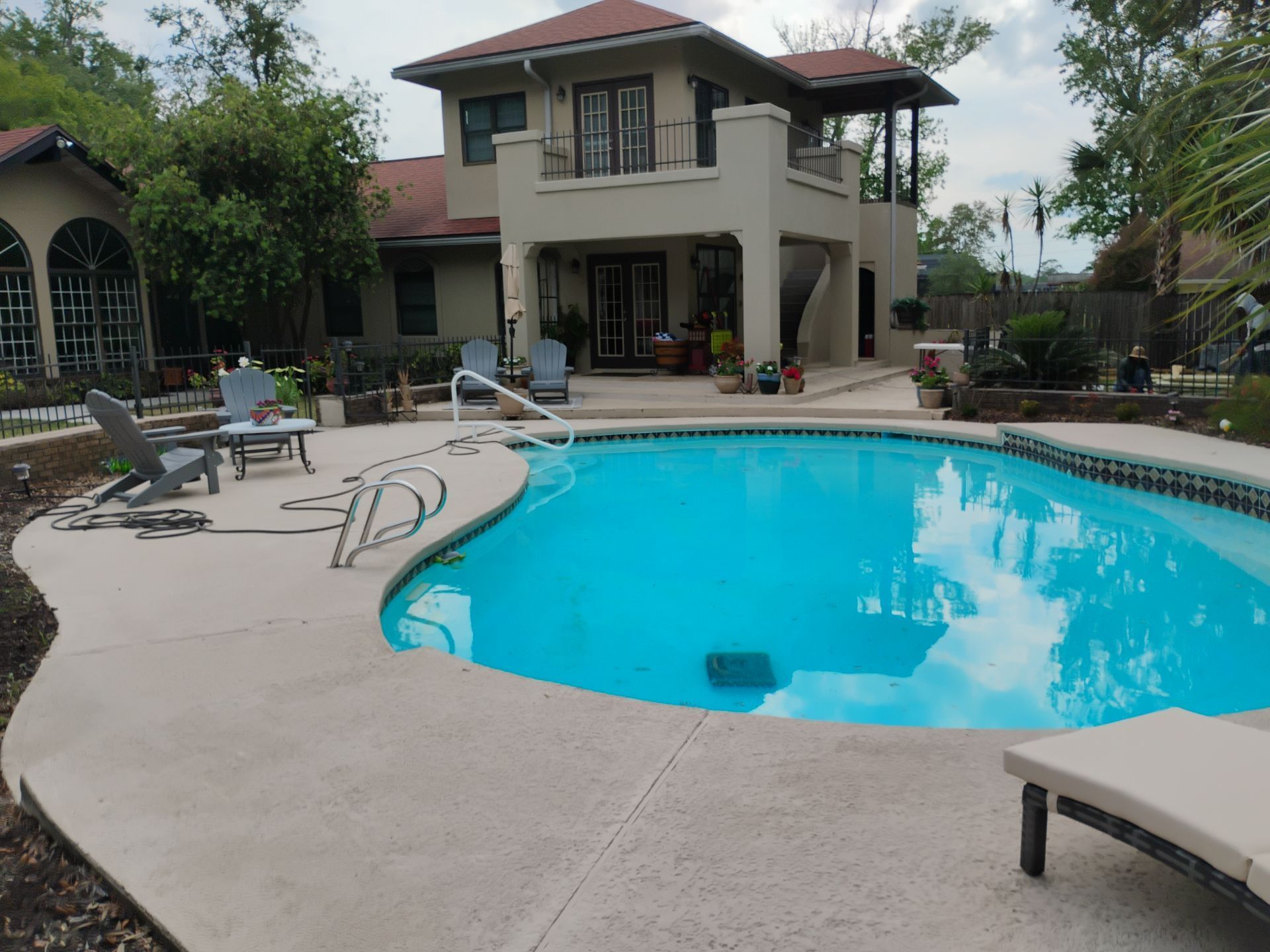 Backyard with a swimming pool and lounge chairs beside a two-story house