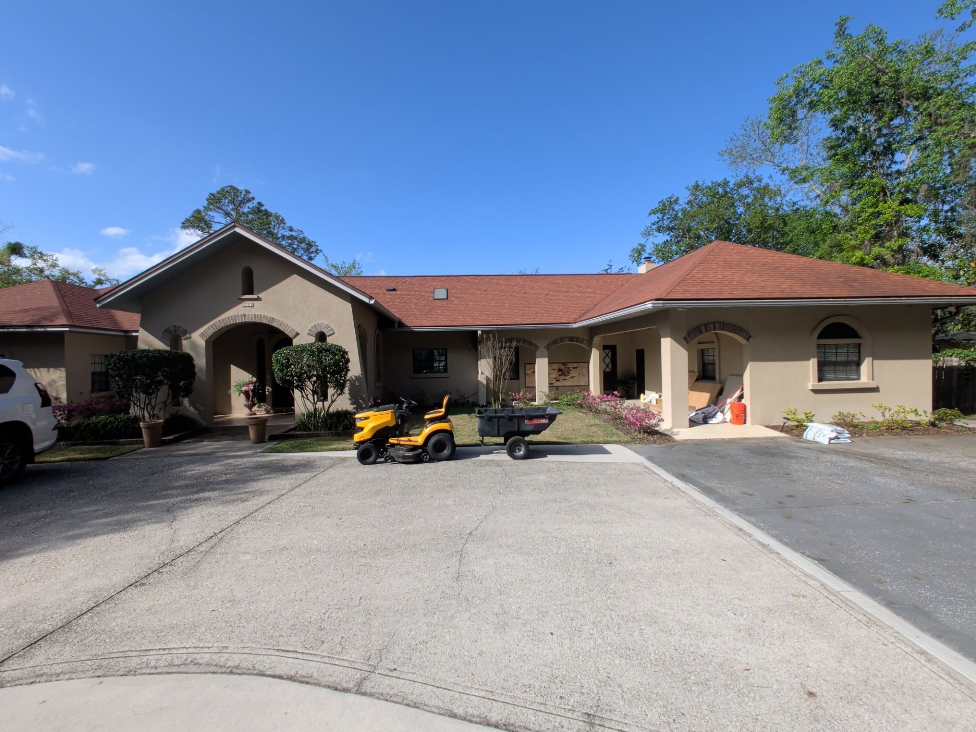 Suburban house with red tile roof, driveway, and a yellow ATV parked in front under a blue sky