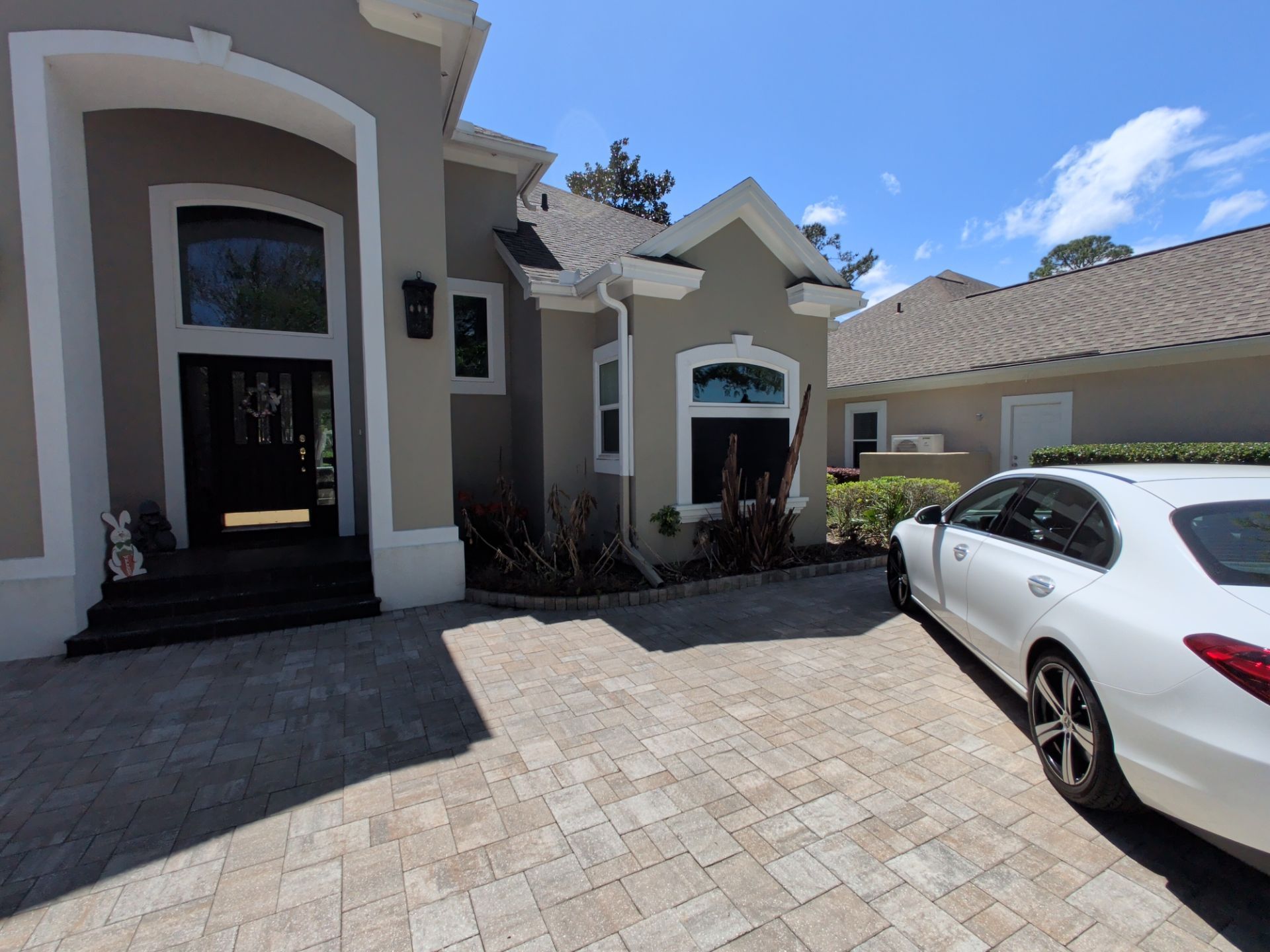 Modern house driveway with a white car parked in front under a blue sky