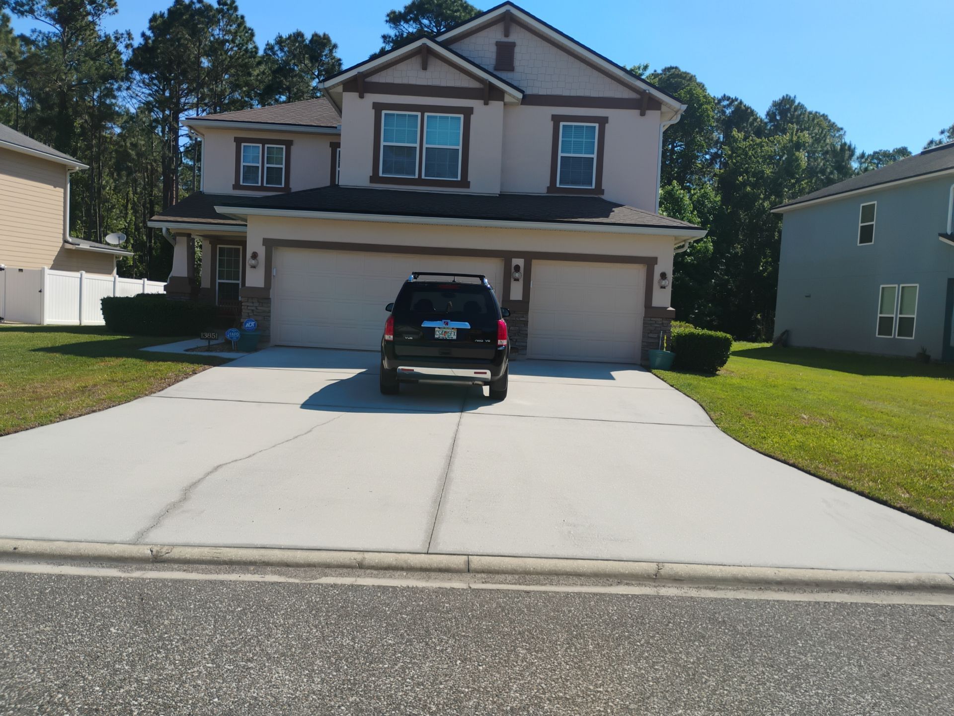 Two-story suburban house with a black SUV in the driveway and a two-car garage.