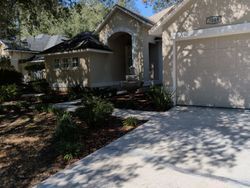 Tan stucco house with a driveway and landscaping.