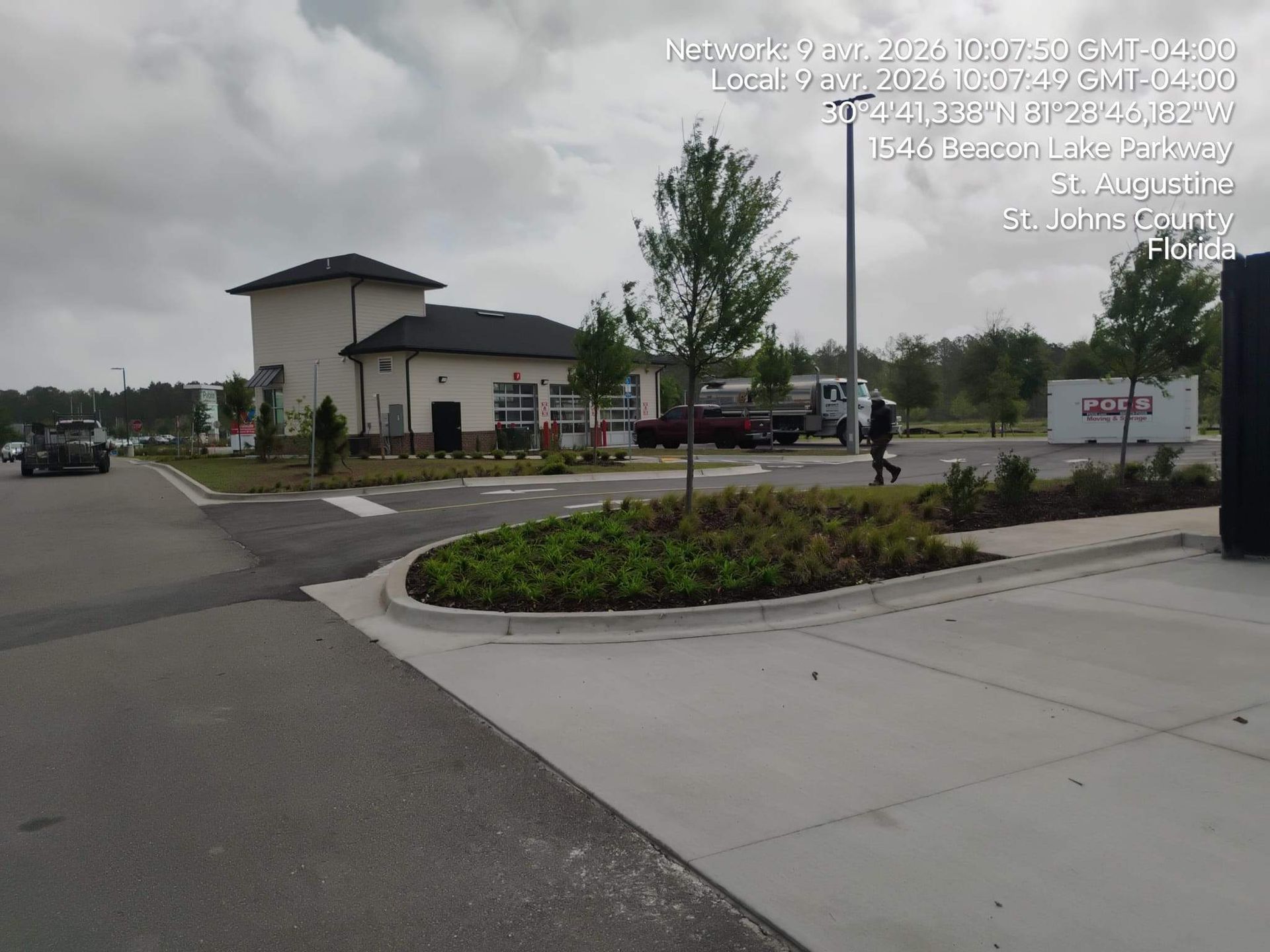 Parking lot with landscaped island and a white building under cloudy skies