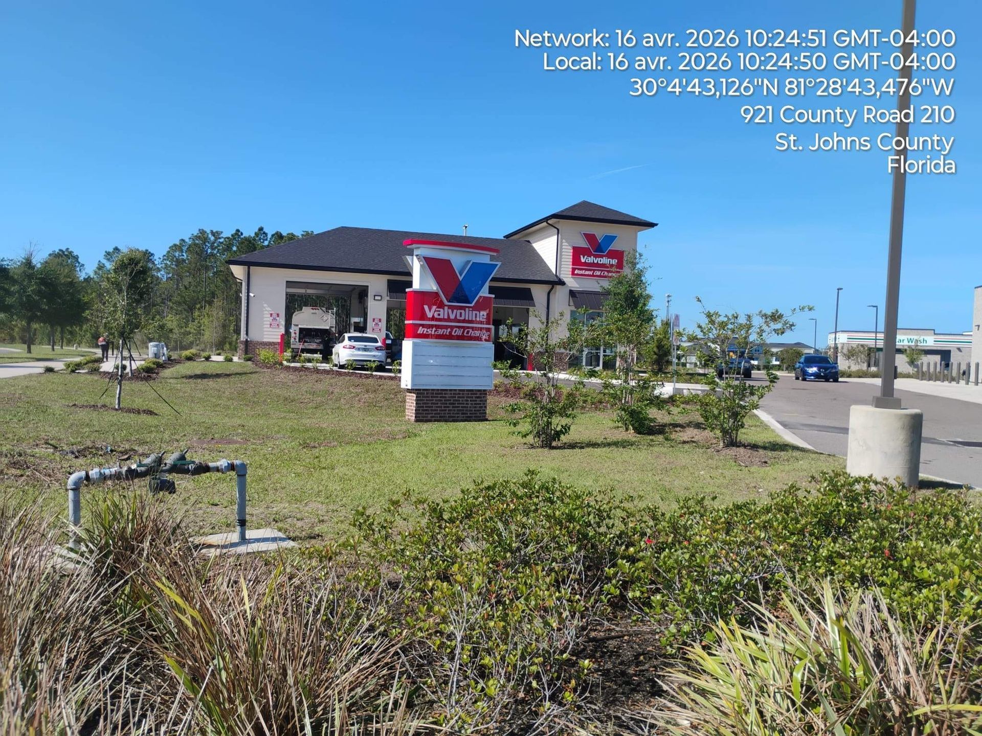 Small building with a red-and-white sign on a grassy roadside under a bright blue sky