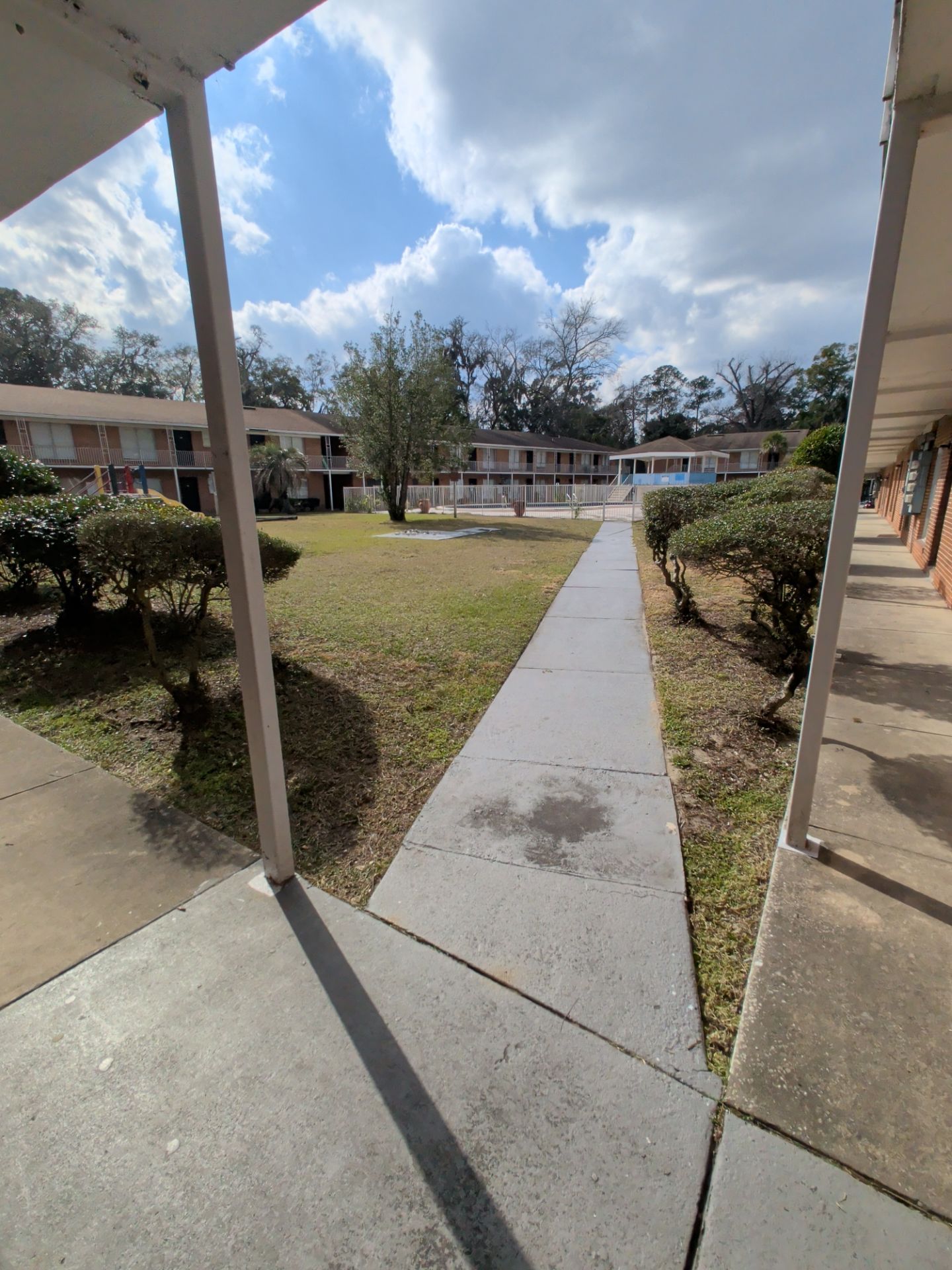 Pathway through apartment complex courtyard, overcast sky.