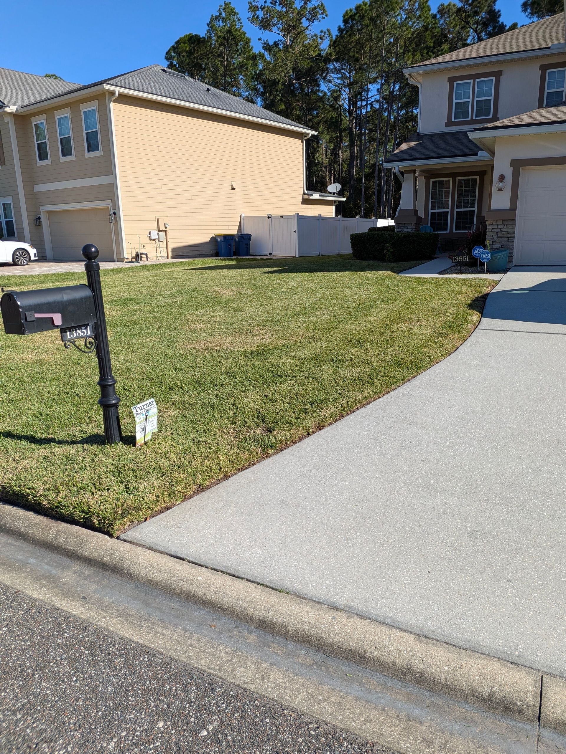 Suburban house with a green lawn and concrete driveway beside a sidewalk and curb.