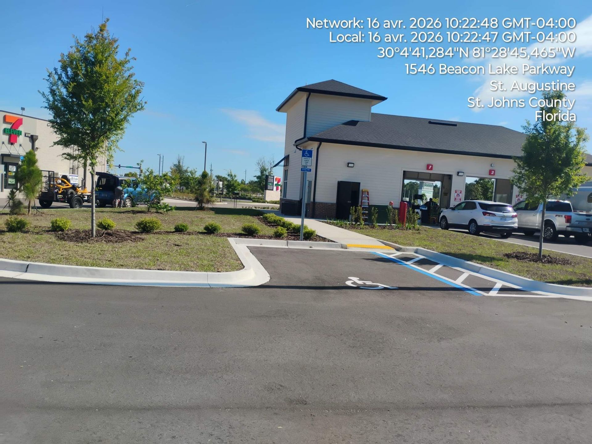 Street view of a parking lot with a small commercial building, trees, and handicap parking spaces