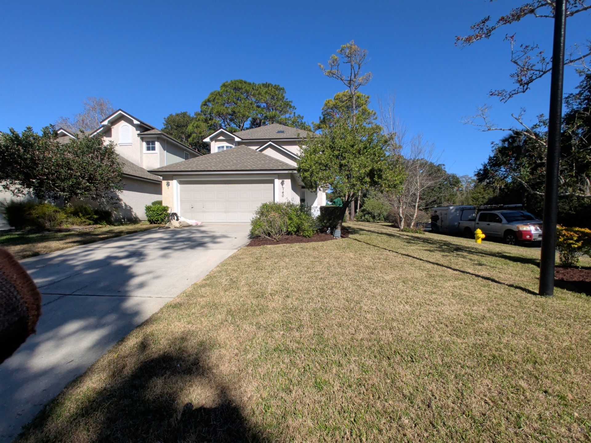 House with a garage and driveway, brown roof, and a lawn. A utility van is parked on the right.