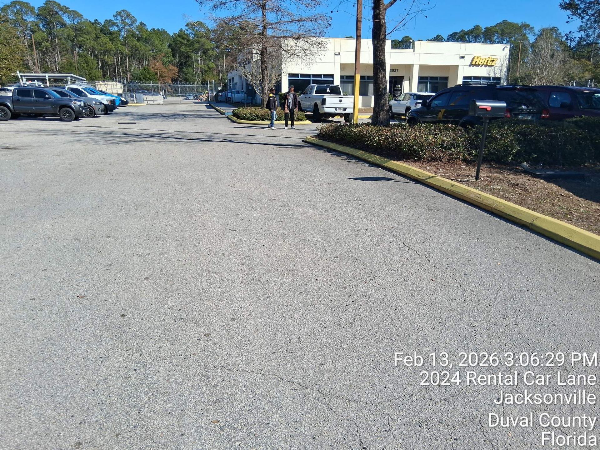 Parking lot with parked cars and a building in the distance on a sunny day