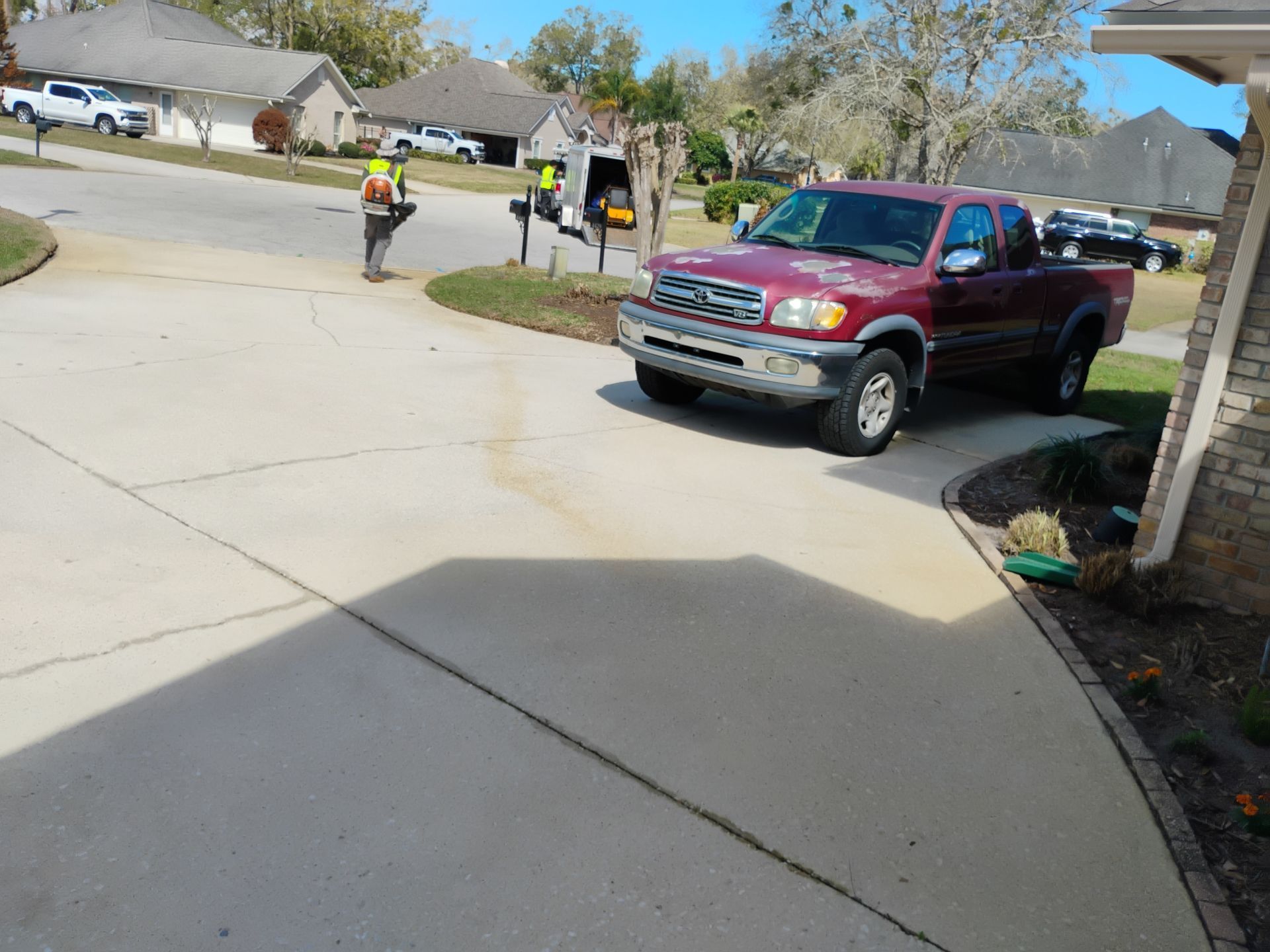Two workers near a red pickup truck on a curved suburban driveway