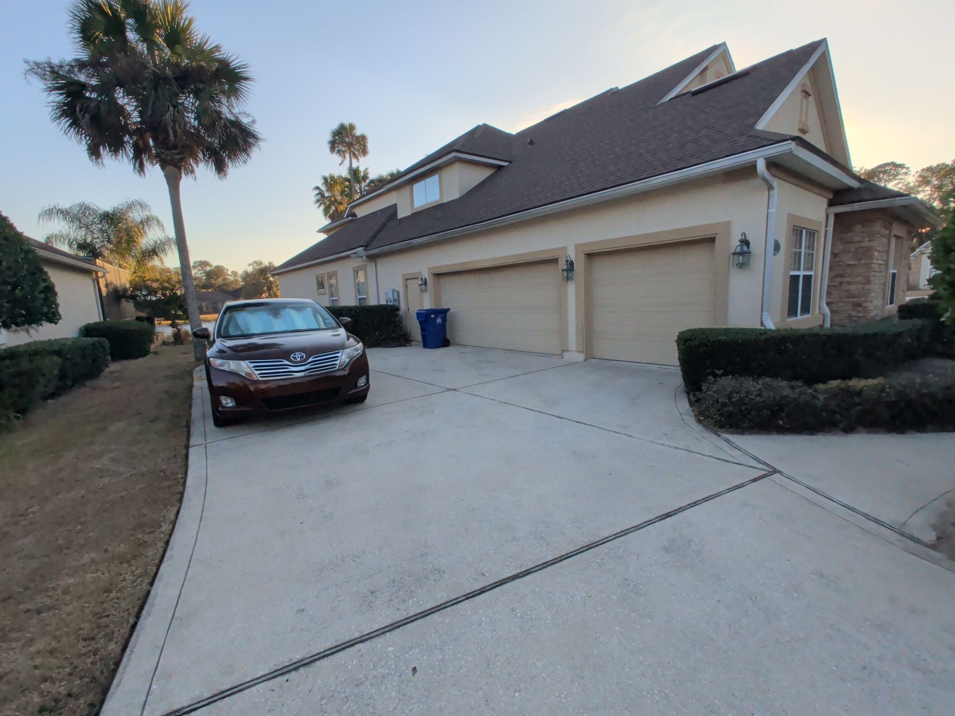 Suburban house driveway with a parked black car and two garage doors at dusk