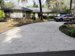 A car parked in a driveway in front of a single-story house with a yard.