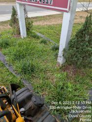 Lawnmower near overgrown grass and a sign with a phone number. Jacksonville, Florida.