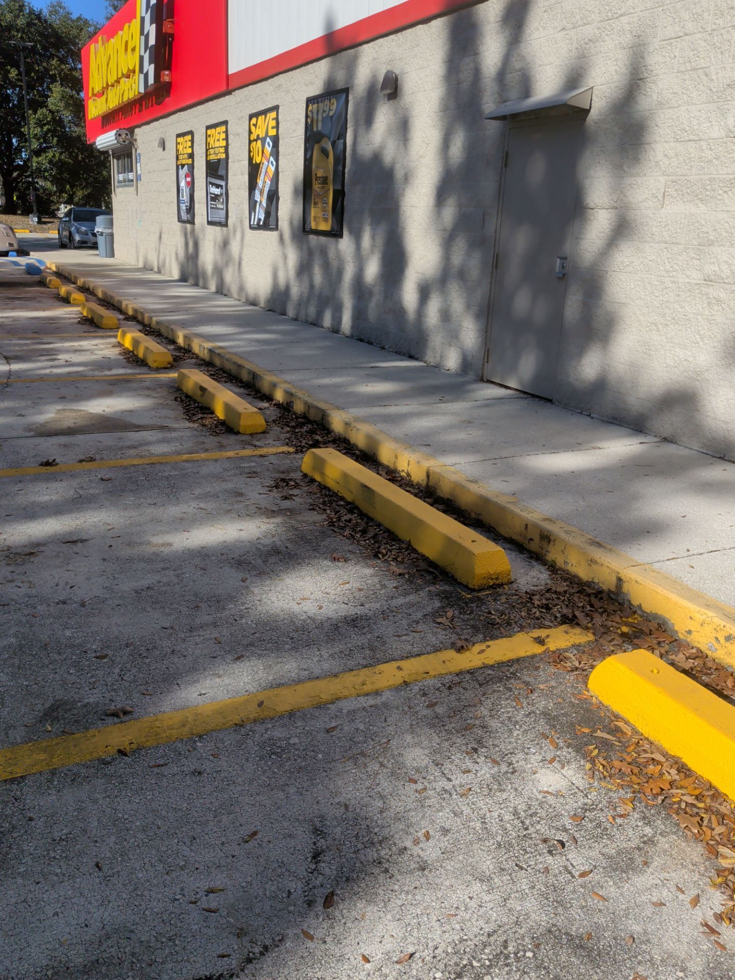 Parking lot with yellow parking blocks in front of a building with red and yellow signage.