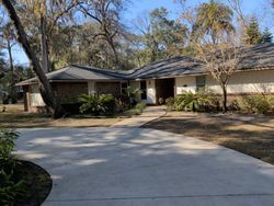 Residential home with gray roof and a wide, circular driveway. Landscaping includes trees and shrubs.