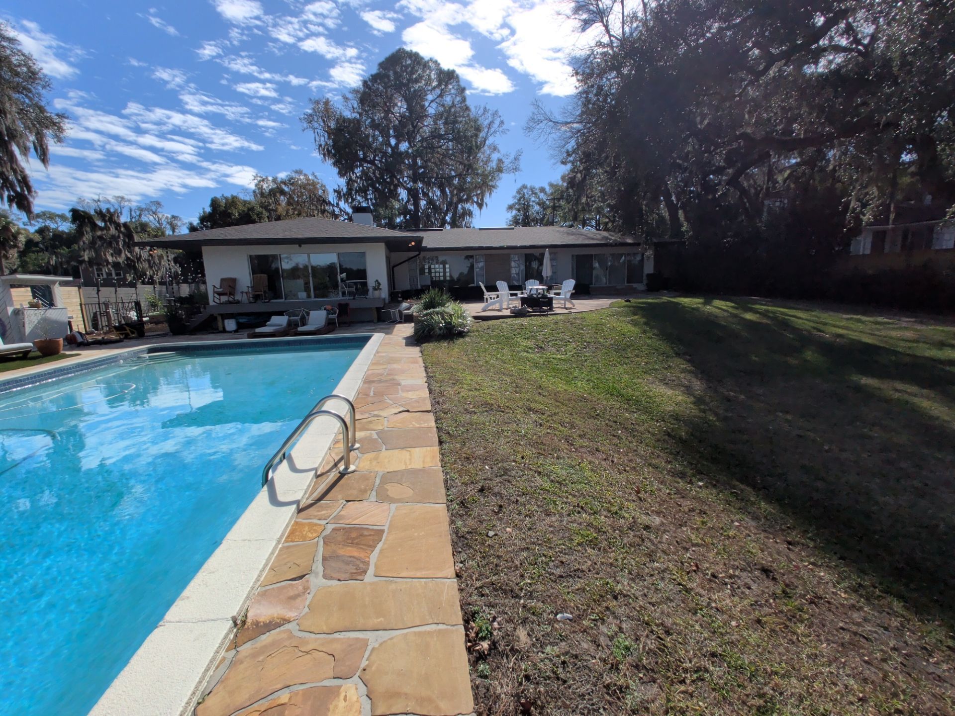 A single-story house with a pool and large backyard on a sunny day.
