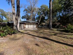 A Japanese-style building with a garage door, surrounded by trees on a sunny day.