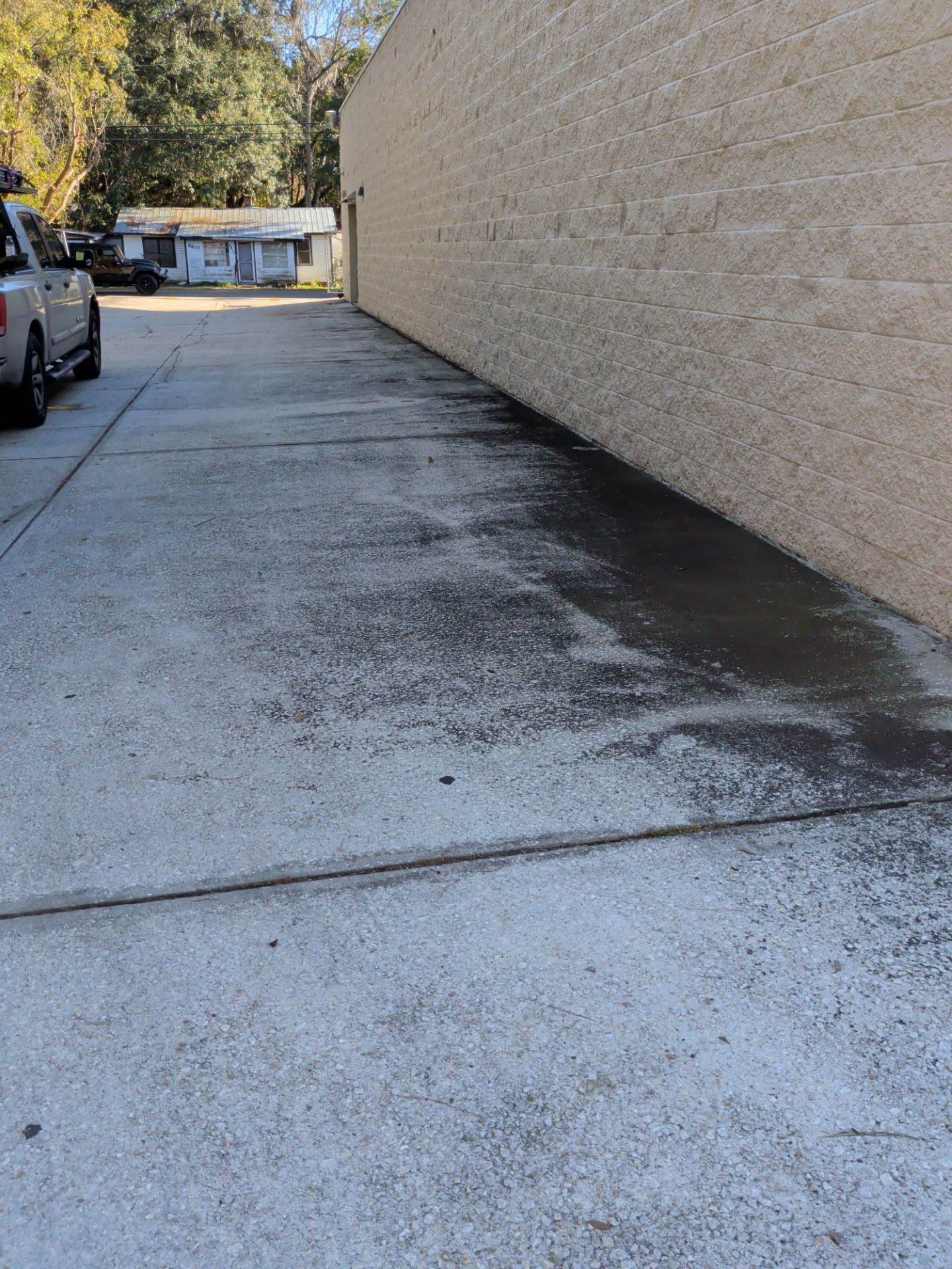 Concrete alleyway next to a beige brick building. A truck is parked on the left.