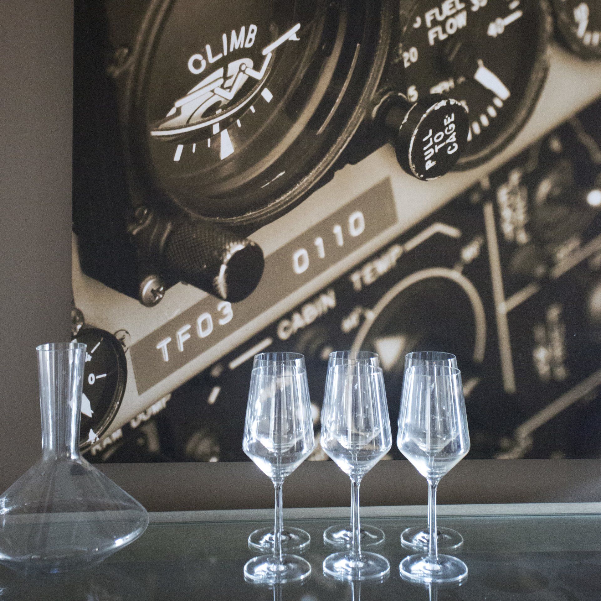 Four wine glasses are on a table in front of a tf03 dashboard