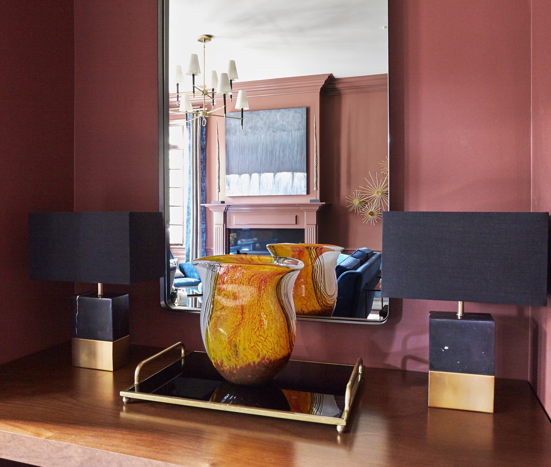 Two lamps and a vase on a table in front of a mirror