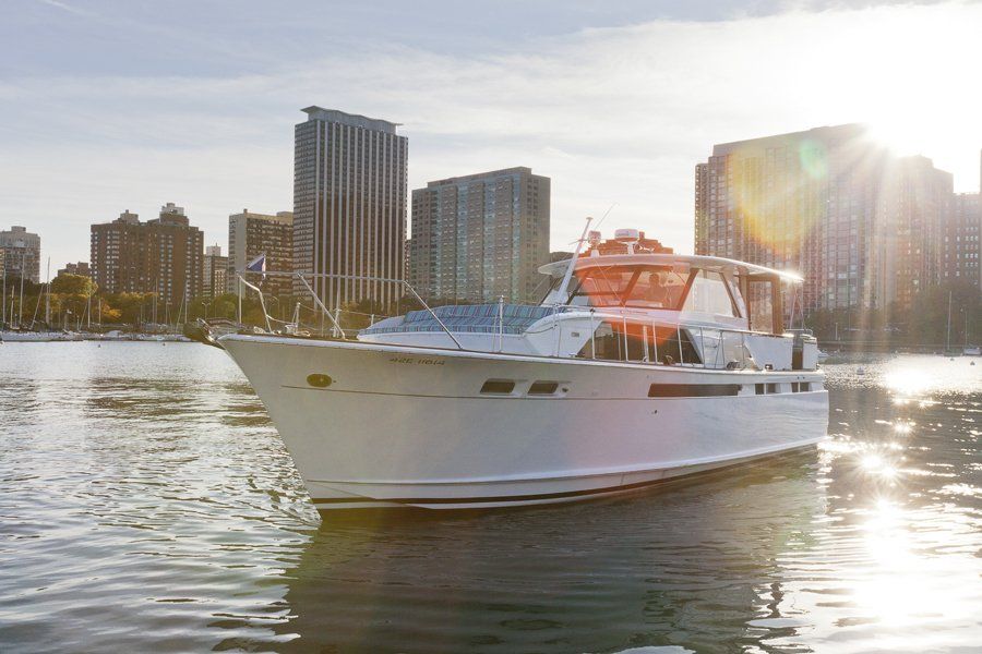 A white boat is floating on top of a body of water in front of a city skyline.