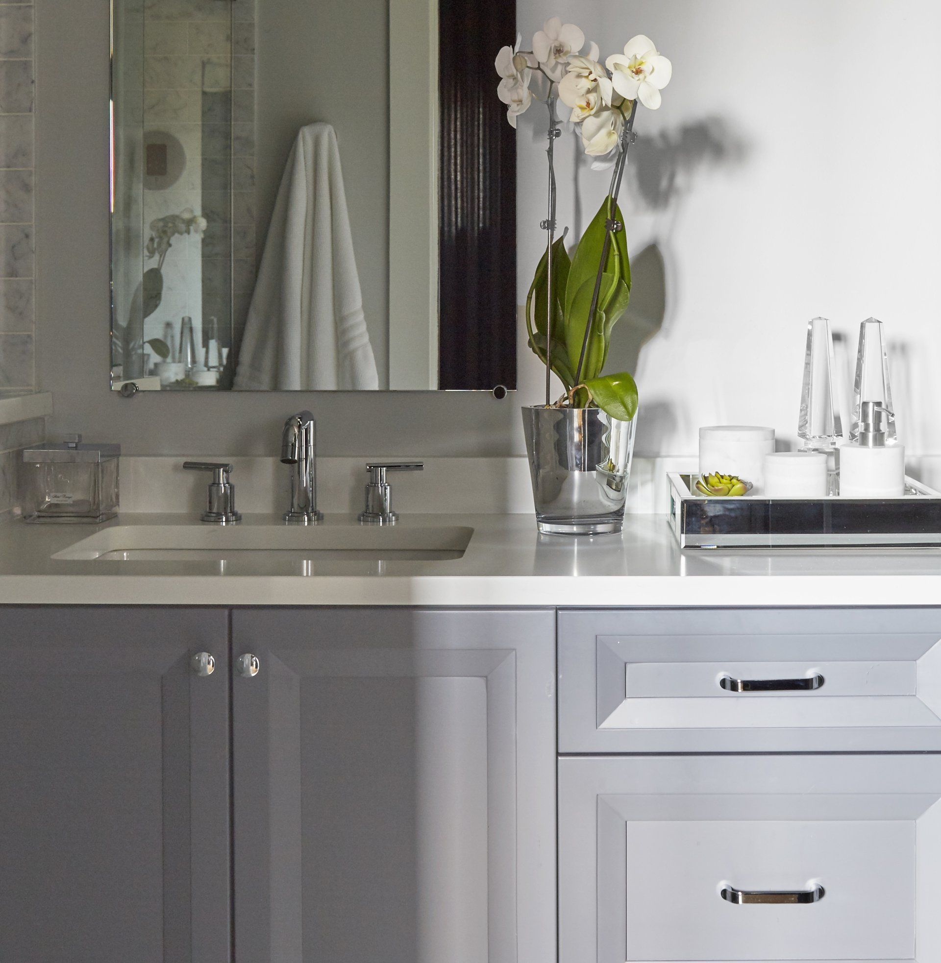 A bathroom with a sink a mirror and a vase of flowers
