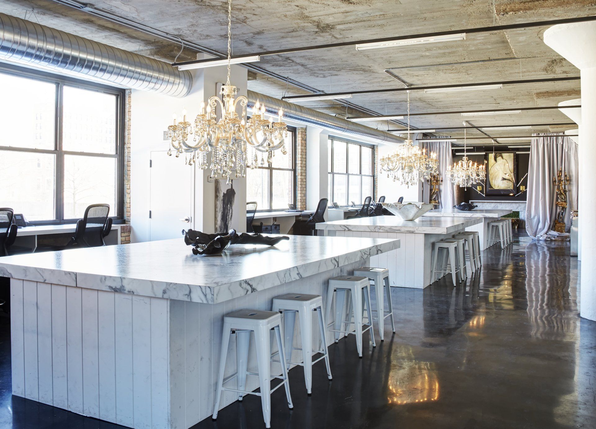 A large room with tables and stools and a chandelier hanging from the ceiling.