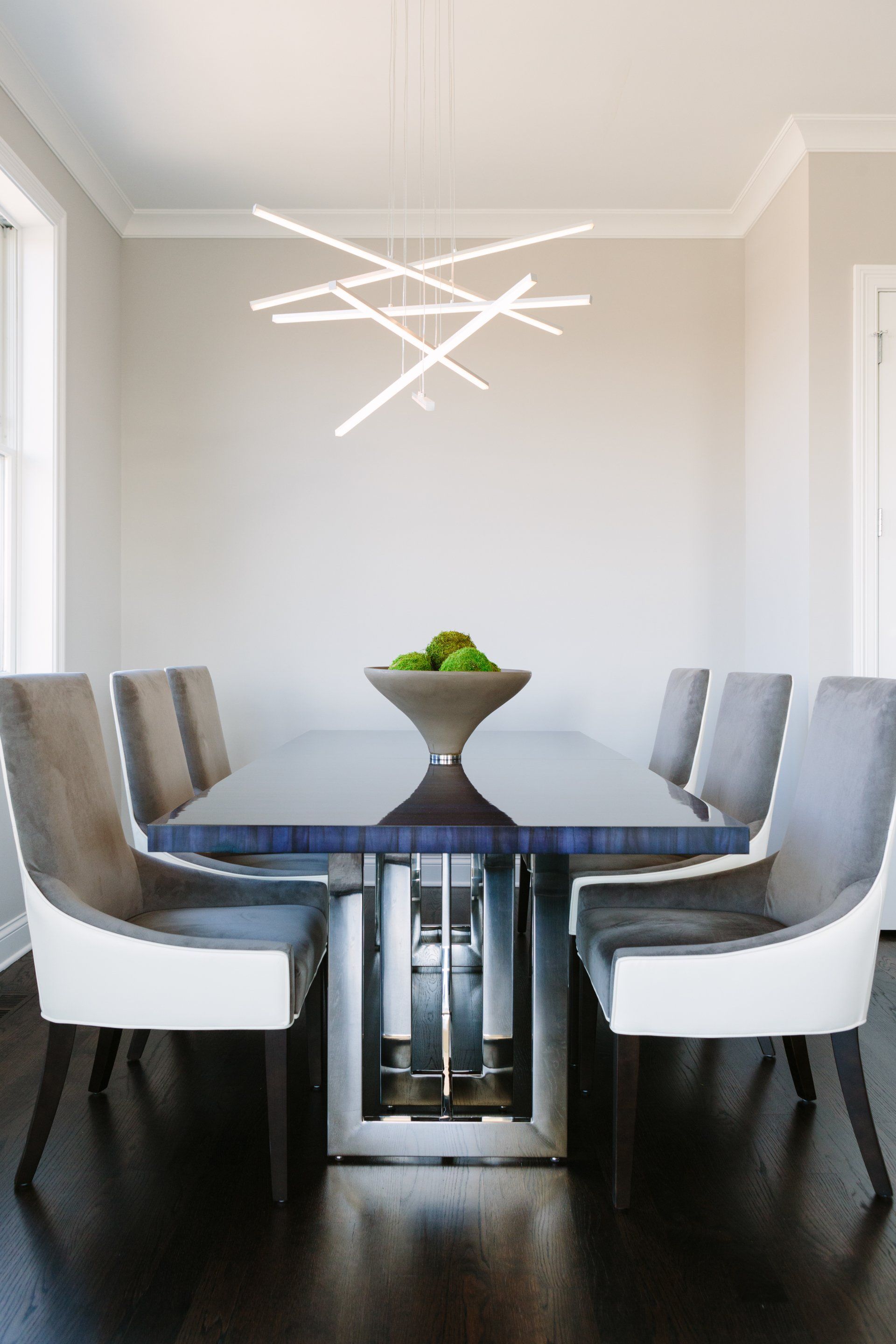 A dining room table and chairs with a bowl of green apples on it.