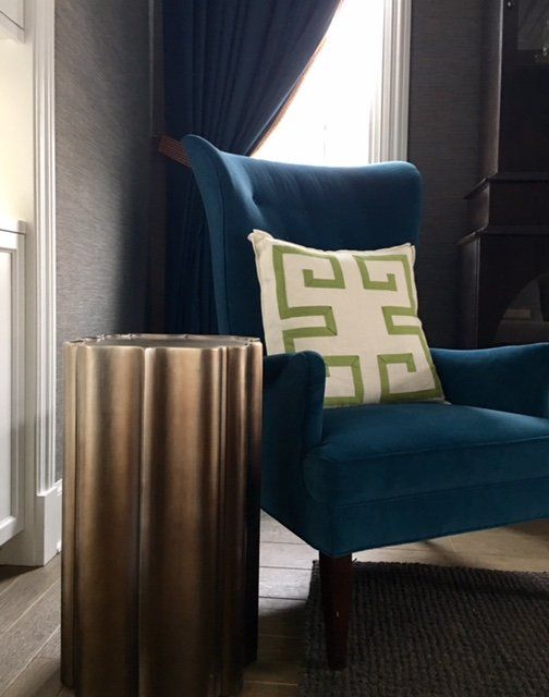 A blue chair with a green and white pillow on it
