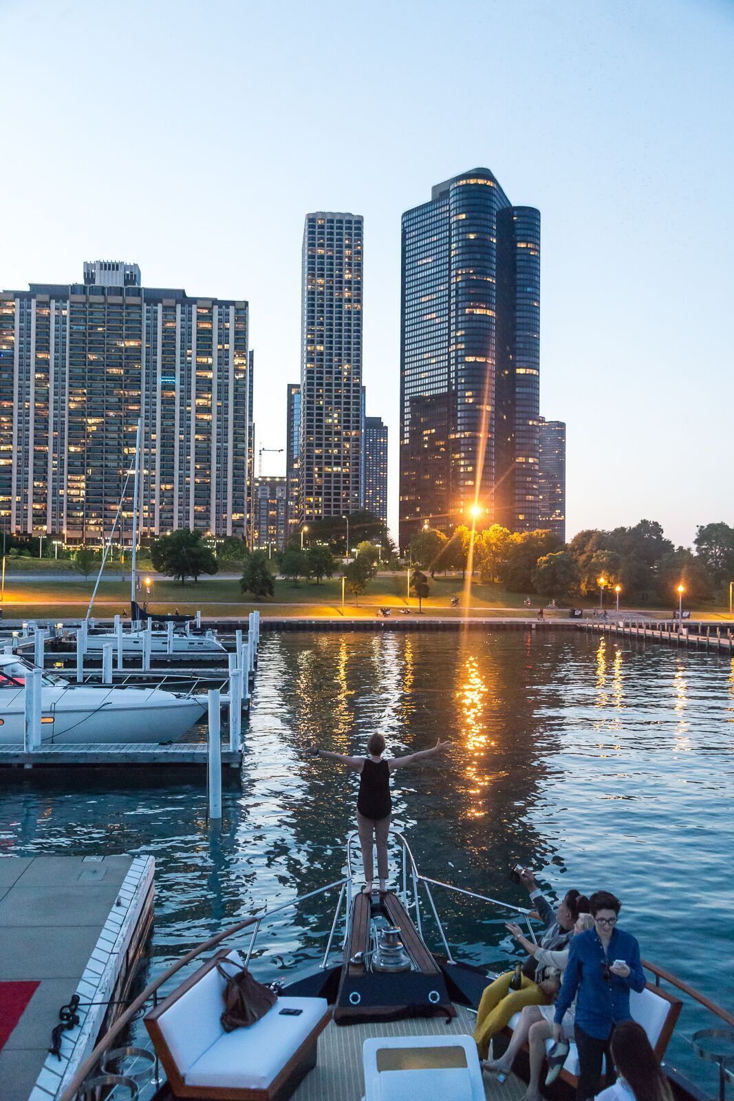A group of people are on a boat in the water with a city in the background.