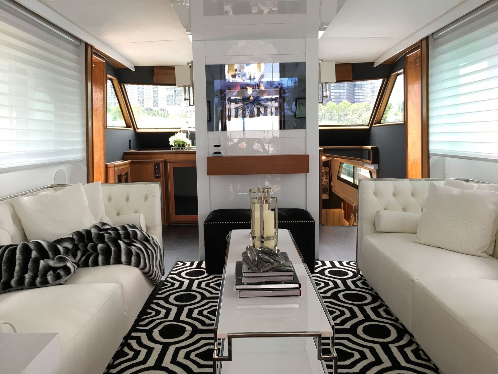 A living room with white couches and a black and white rug