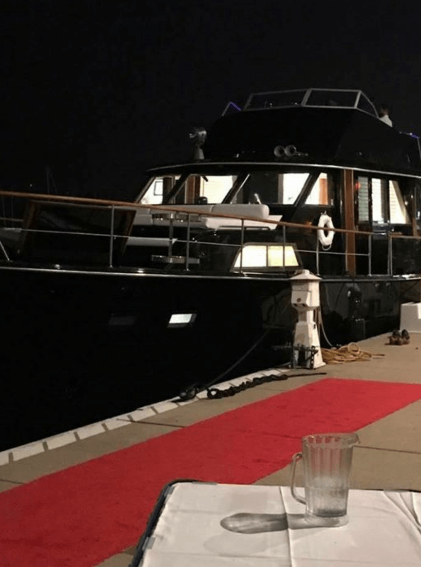 A boat is docked next to a table with a glass of water on it