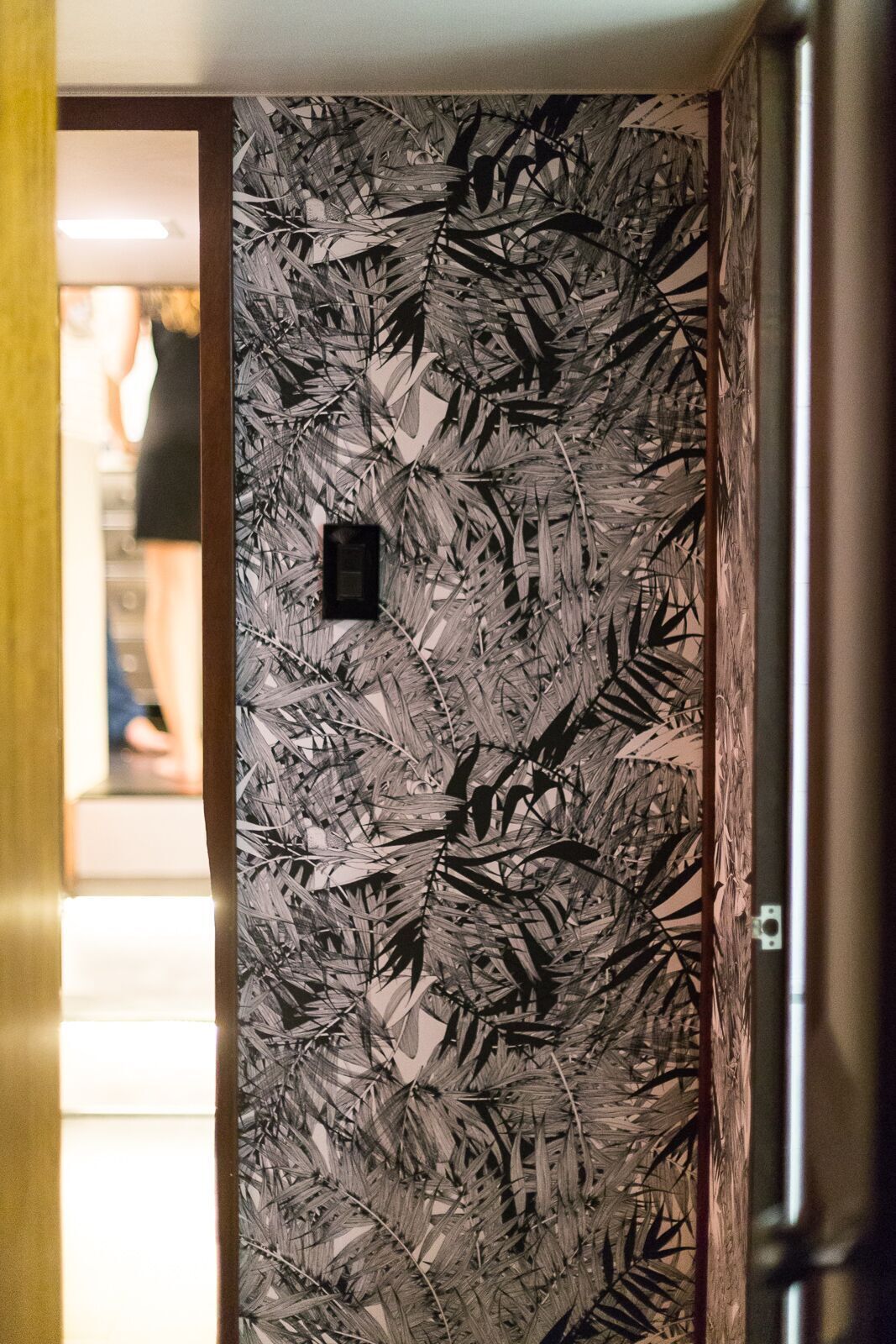 A hallway with a black and white floral wallpaper on the wall.