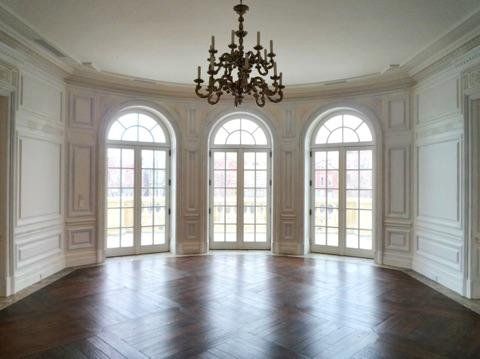 A large empty room with arched windows and a chandelier.