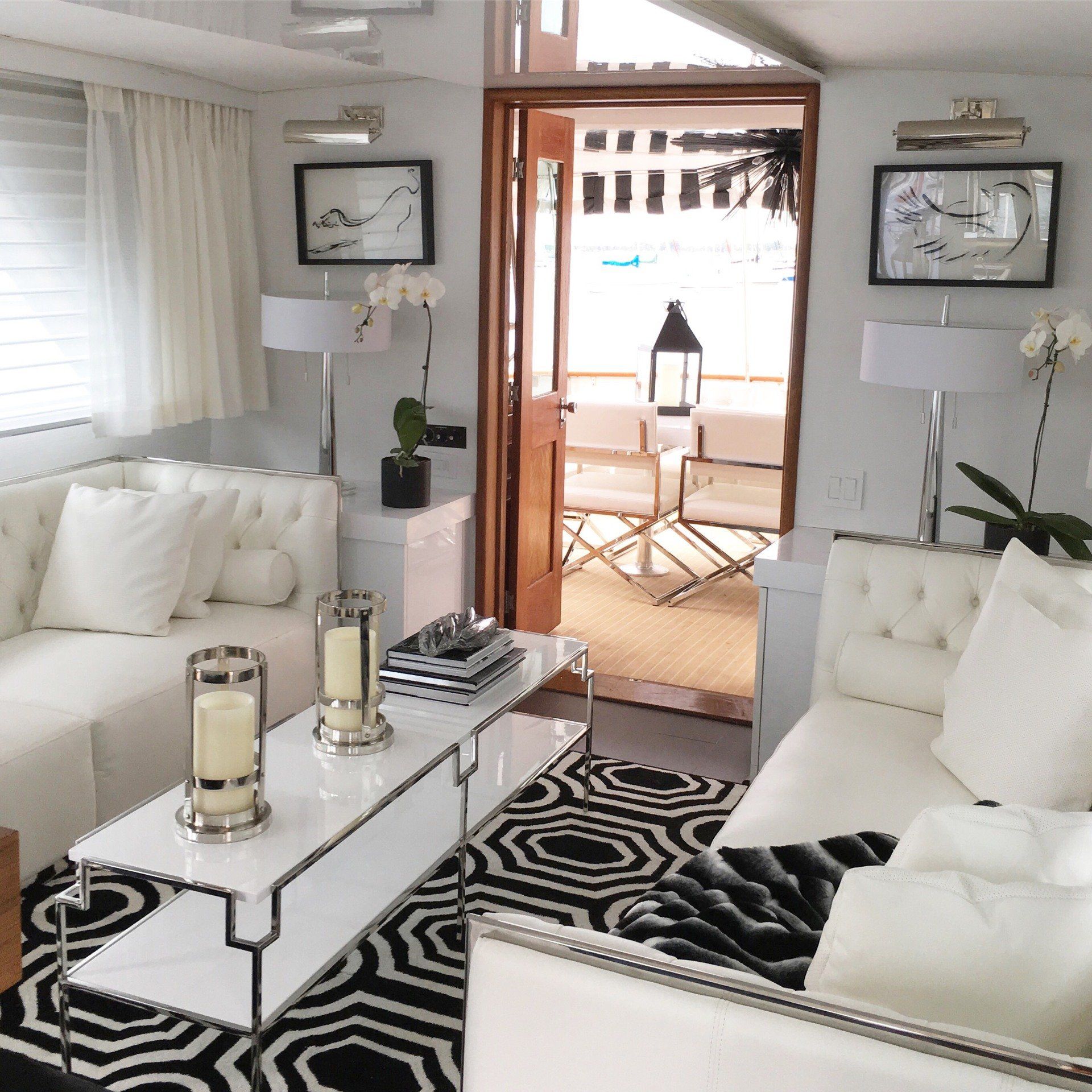 A living room with white furniture and a black and white rug
