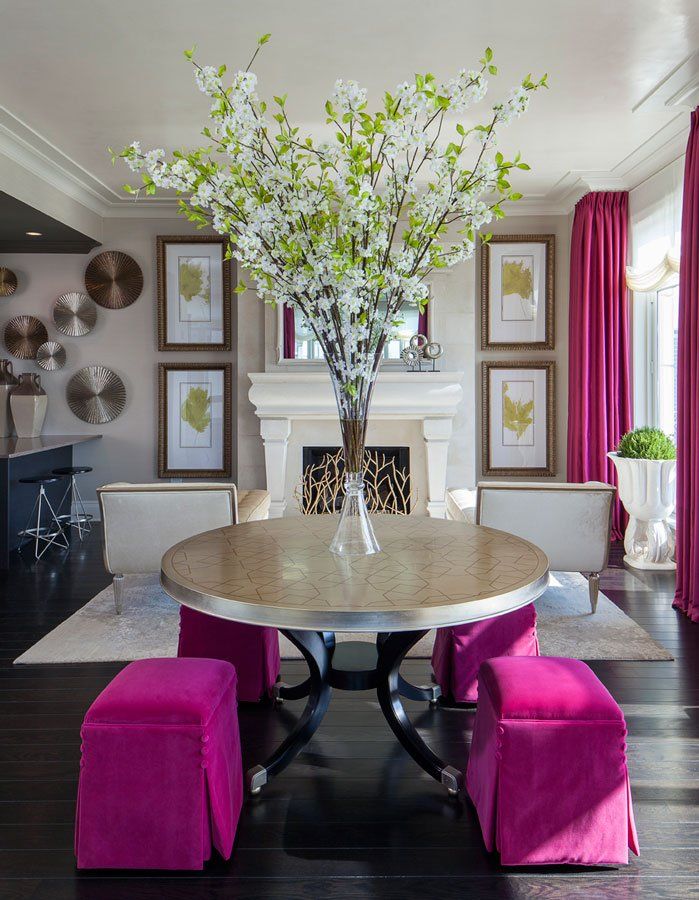 A living room with a round table and pink ottomans