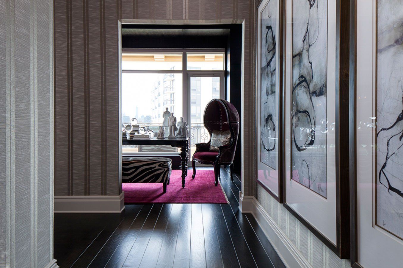 A hallway leading to a living room with paintings on the wall.