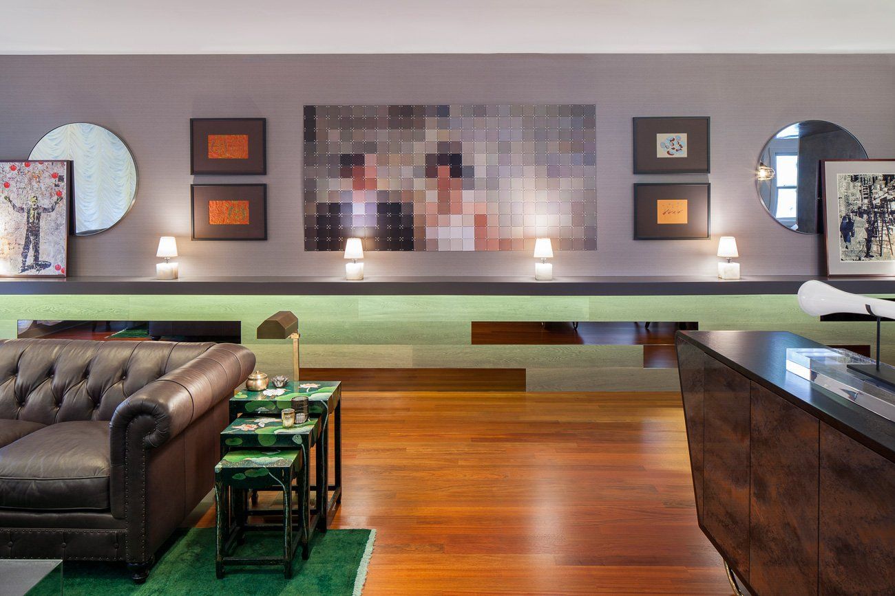 A living room with a brown leather couch and a green rug