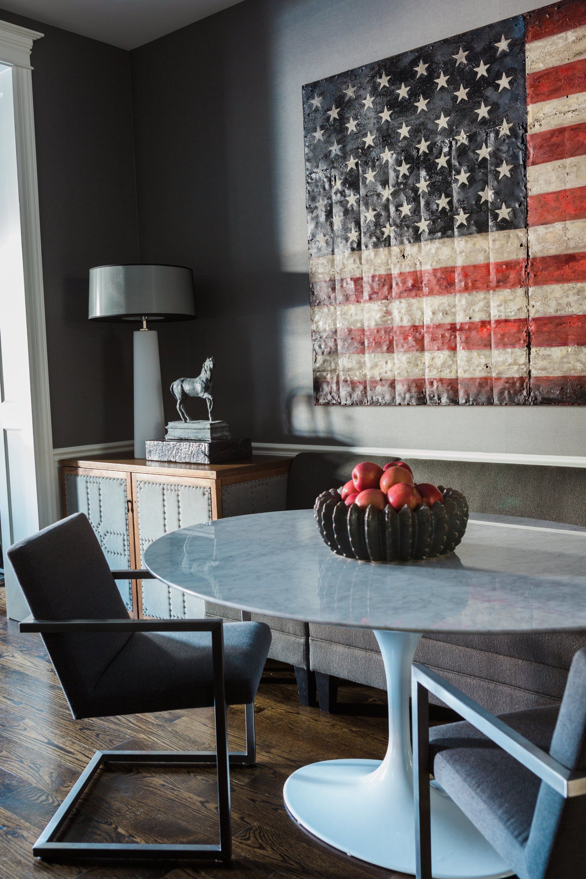 A dining room with a table and chairs and an american flag on the wall.