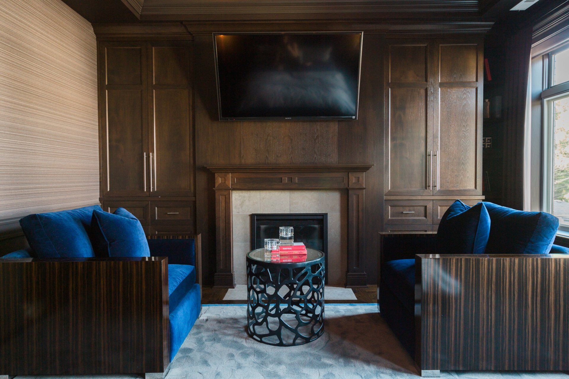 A living room with two couches , a table , a fireplace and a flat screen tv.